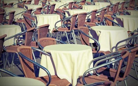 Many tables of an alfresco bar with lots of chairs and vintage effect Фото