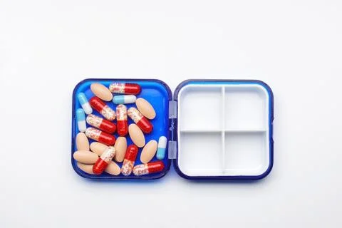 Many tablets and capsules in a plastic container on a white background Stock Photos