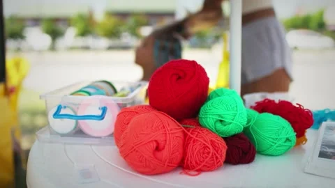 Many threads and ribbons lie on the table against the background of a girl whose Stock Footage 348086249