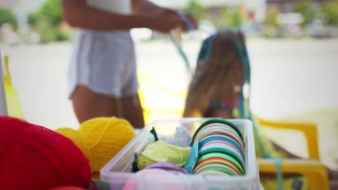 Many threads and ribbons lie on the table against the background of a girl whose Stock Footage 348131908