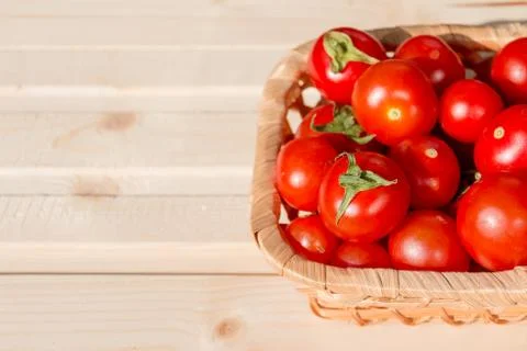 Many tomatoes called cherry tomato in the basket on wooden table, fresh organic Stock Photos
