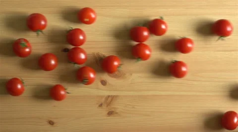 Many tomatoes roll on a wooden surface. Slow Motion. Top view. Stock Footage 67730076