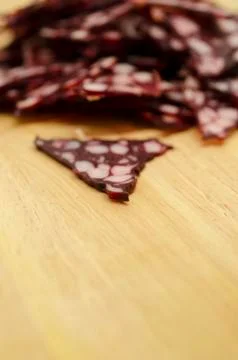 Many triangular pieces of sausage with fat on wooden background 스톡 사진