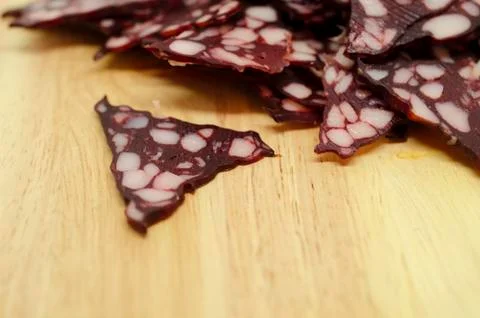 Many triangular pieces of sausage with fat on wooden background 스톡 사진