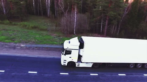 Many trucks driving on the freeway towards the setting sun. Rush hour on the Stock Footage 67902965