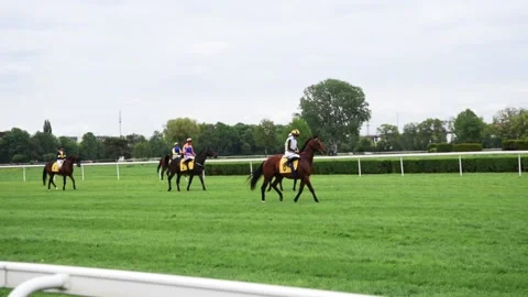 Many unrecognisable jockeys on horseback run to the finish line at the green  Stock Footage 201341876