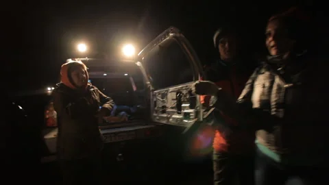 Many volunteers at night by the light of lanterns next to the patrol car Stock Footage 166697954