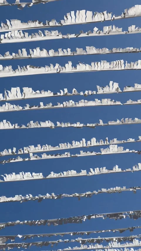 Many weathered white pennant banners hanging on cords and swaying in the brisk Stock Footage 345520863