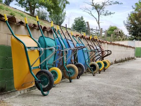 Many wheelbarrows for removing garbage of different colors in a row Stock Photos