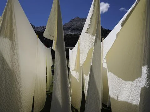 Many white bed sheets drying to the sun in mountain Stock Photos