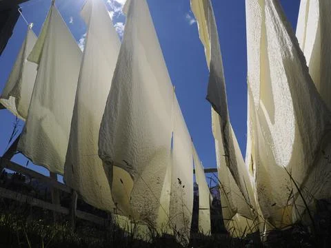 Many white bed sheets drying to the sun in mountain Stock Photos