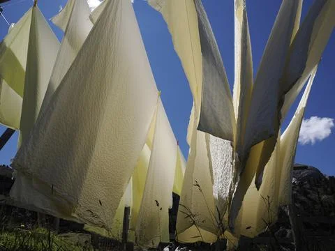 Many white bed sheets drying to the sun in mountain Stock Photos
