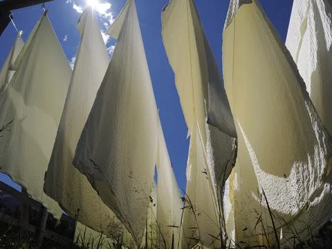 Many white bed sheets drying to the sun in mountain Stock Photos