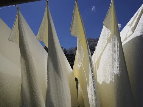 Many white bed sheets drying to the sun in mountain Stock Photos