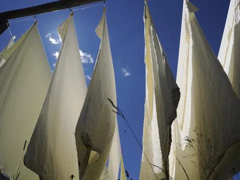 Many white bed sheets drying to the sun in mountain Stock Photos