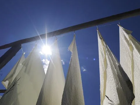 Many white bed sheets drying to the sun in mountain Stock Photos