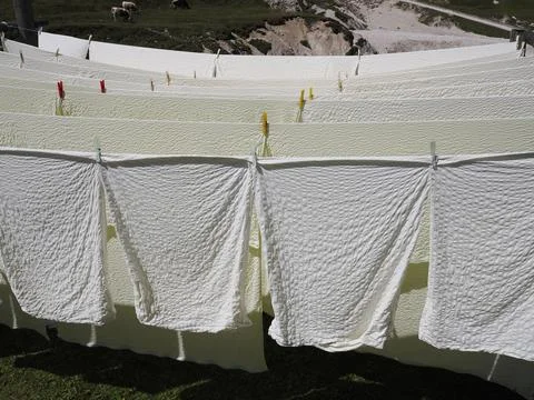 Many white bed sheets drying to the sun in mountain Stock Photos