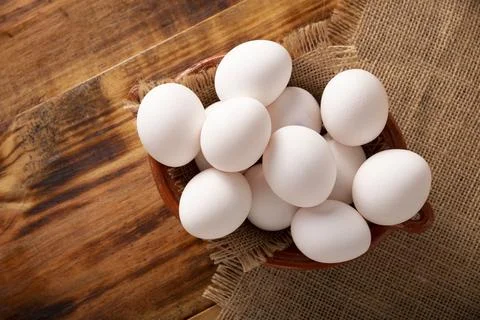 Many white chicken eggs on rustic wooden table. Very popular nutritious and e Stock Photos