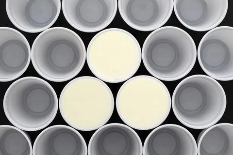 Many white plastic disposable cups, tree are filled with milk Stock Photos