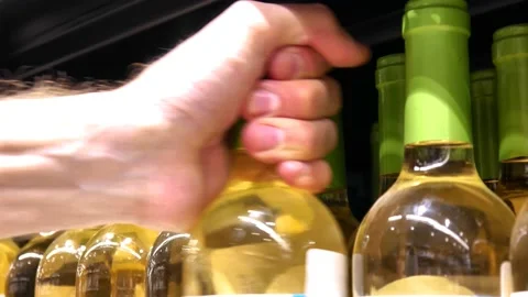 Many white wine bottles on a store shelf and a buyer's hand takes one Stock Footage 218128134