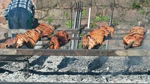 Many whole bacon roasted on a spit over charcoal during a village party Stock Footage 103411201