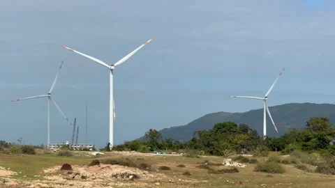 Many wind turbines spin across open territory, creating a wide wind farm scene 動画素材 329304620