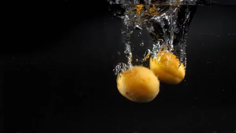 Many yellow apricots fall into the water with spray, slowly sinking to the botto Stock Footage 133354007
