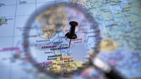 Map focus on Copenhagen marked with a pin viewed through magnifying glass Stock Photos