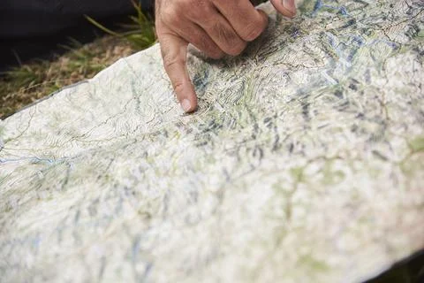 A map on the ground, one hand points to a place. Concept: orientation in natu Stock Photos