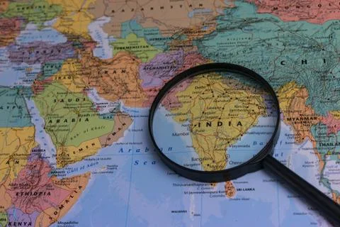 Map of India through magnifying glass on a world map. Stock Photos