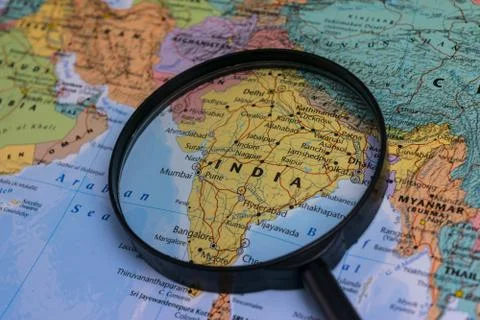 Map of India through magnifying glass on a world map. Stock Photos