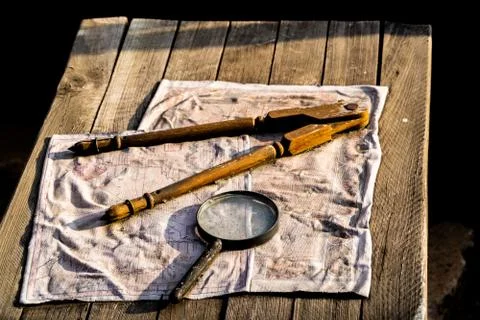 Map, magnifying glass and drafting compass on distressed wooden table Stock Photos