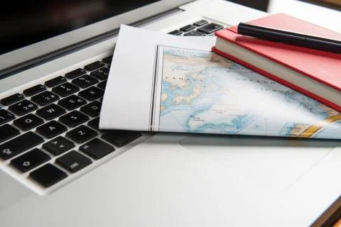 Map, notebook and ball-point pen on laptop Stock Photos