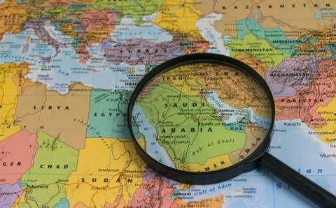 Map of Saudi Arabia through magnifying glass on a world map. Stock Photos