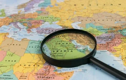 Map of Saudi Arabia through magnifying glass on a world map. Stock Photos