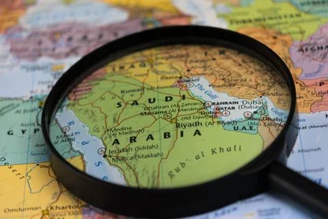 Map of Saudi Arabia through magnifying glass on a world map. Stock Photos
