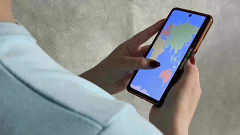 Map of the world on the phone screen in the hands of a woman 스톡 동영상 334794322