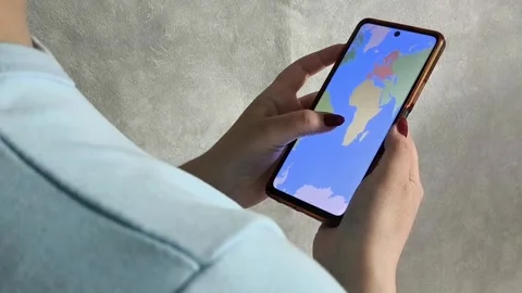 Map of the world on the phone screen in the hands of a woman 스톡 동영상 334794468