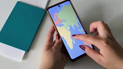 A map of the world on the phone screen in the hands of a woman Vídeo Stock 334794873