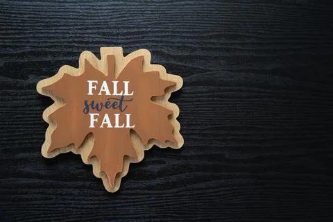 Maple leaf with Fall Sweet Fall printed on it, on a black wooden background.. Stock Photos
