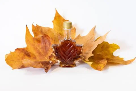 Maple leaf shape bottle with maple leaf syrup with maple Autumn leaf's on w.. Stock Photos