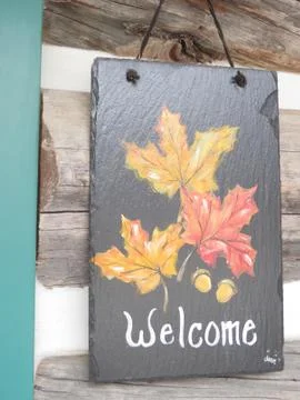 Maple leaf Welcome sign hung outdoors on rustic building Stock Photos