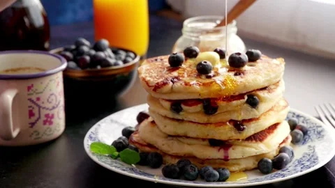 Maple Syrup being poured onto blueberry's and a stack of American pancakes. Vídeo Stock 336589109