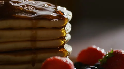 Maple syrup being poured over warm stacked pancakes with fruit, in slow motion Stock Footage 65281499
