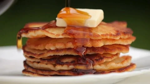 Maple syrup being poured on stack of steaming buttered pancakes. Stock-Footage 336589028