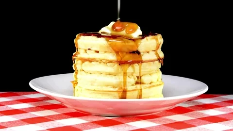 Maple syrup being poured on stack of steaming buttered pancakes. Stock-Footage 336589066