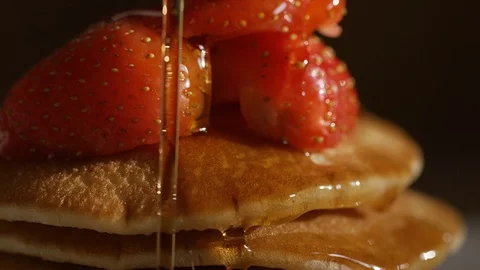 Maple syrup drizzled over stacked pancakes and strawberries Видео 74221138
