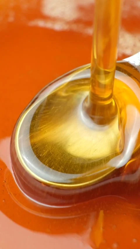 Maple syrup pouring onto a spoon macro vertical slow motion. Stock Footage 335877275