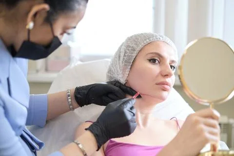 Mapping out the client's face for optimal cheek elevation. Seeking youthful Stockfoto's