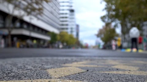 Marahon runners in a city pass by a camera with camera focus on the floor Stock Footage 98033749